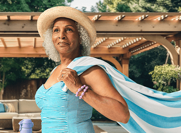 Woman in baby blue swimsuit with blue and white striped towel flowing over her shoulder