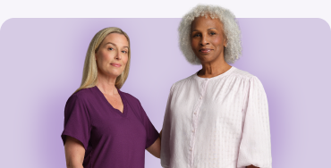 Nurse with burgundy scrubs and woman in white t-shirt smiling with purple background