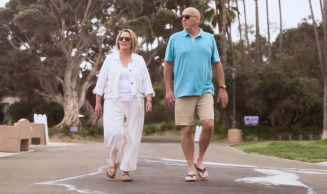 Woman in white shirt and pants walking with man in blue shirt and khaki shorts