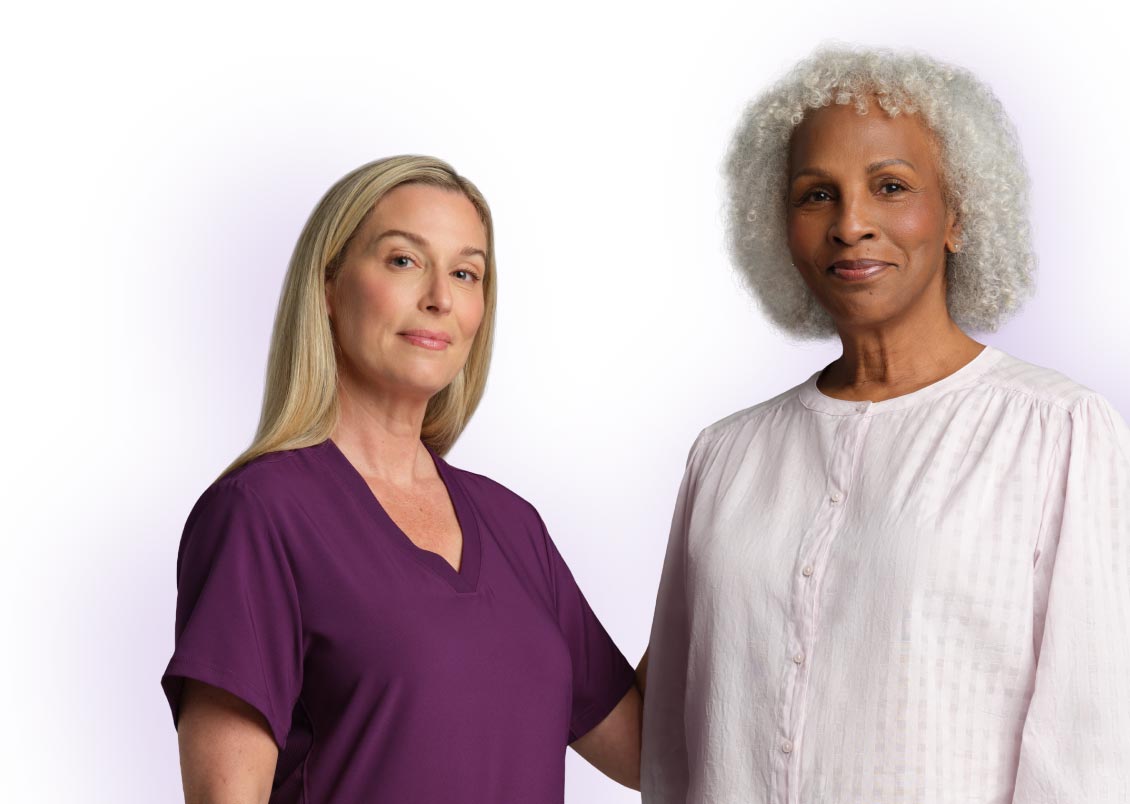 Nurse with burgundy scrubs and woman in white t-shirt smiling